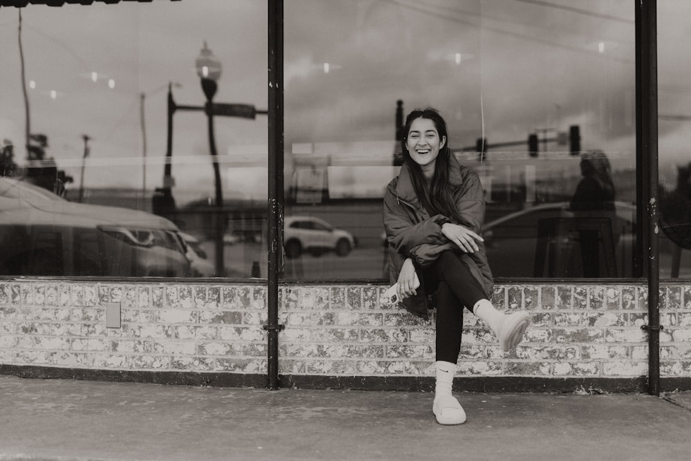 a black and white photo of a woman sitting in front of a window