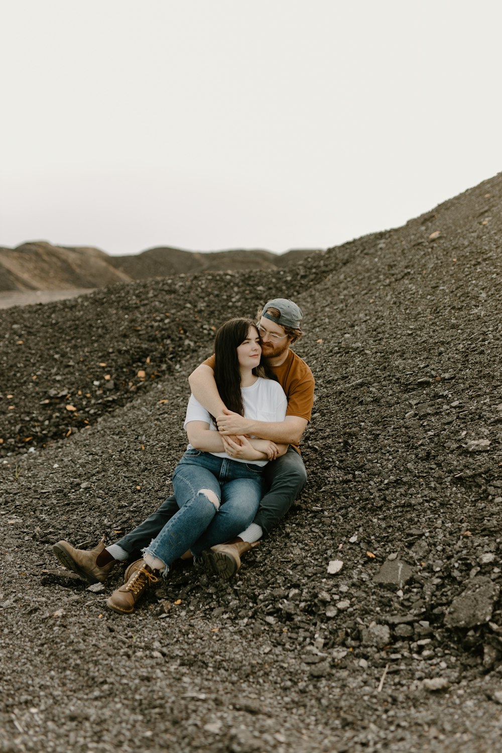 a man and a woman sitting on top of a pile of dirt