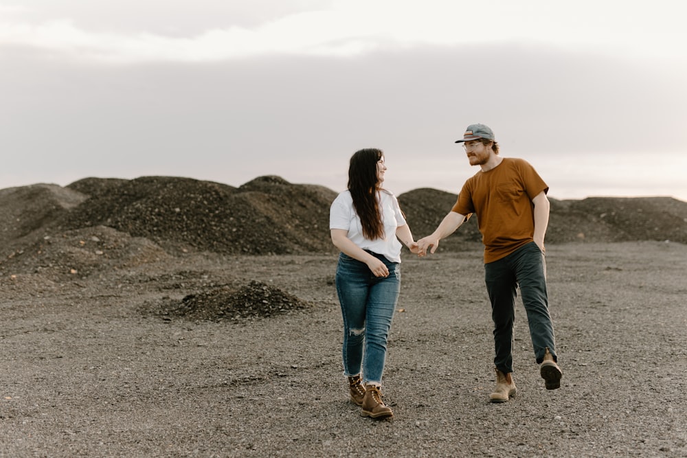 a man and a woman holding hands and walking in the desert