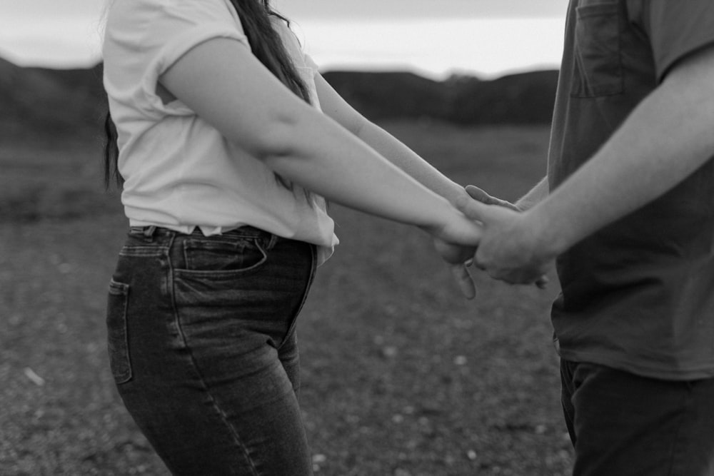 a man and a woman holding hands in a field