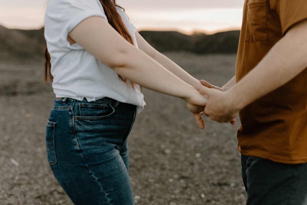 a man and a woman holding hands in the desert