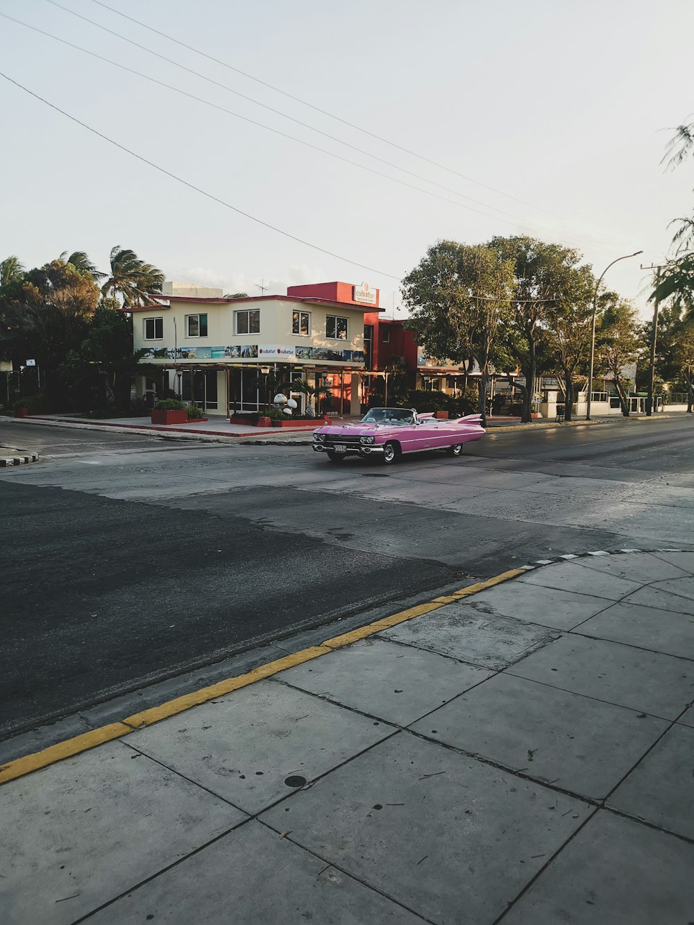un'auto rosa parcheggiata sul ciglio della strada