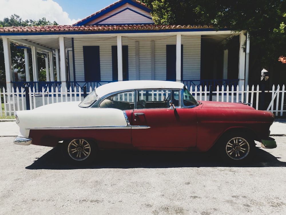 a red and white car parked in front of a house