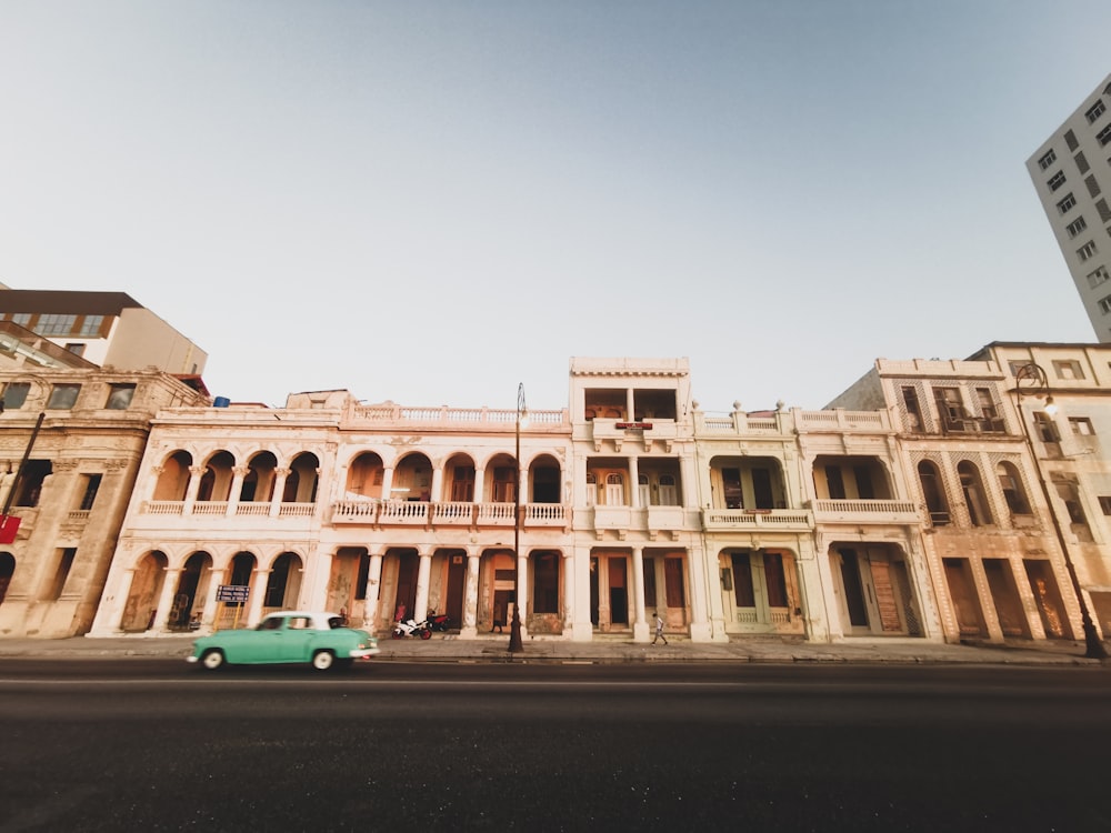 a green car is parked in front of a building