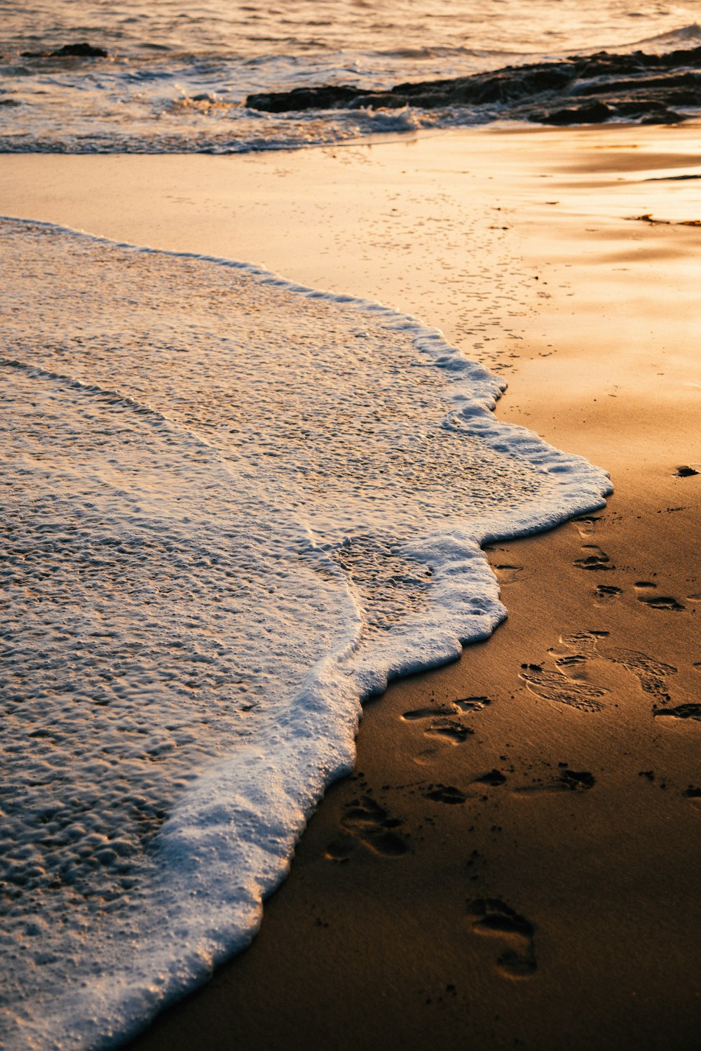 footprints in the sand of a beach at sunset