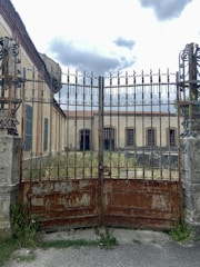Rusty gate with jagged teeth-like iron bars, shrouded in creeping fog.