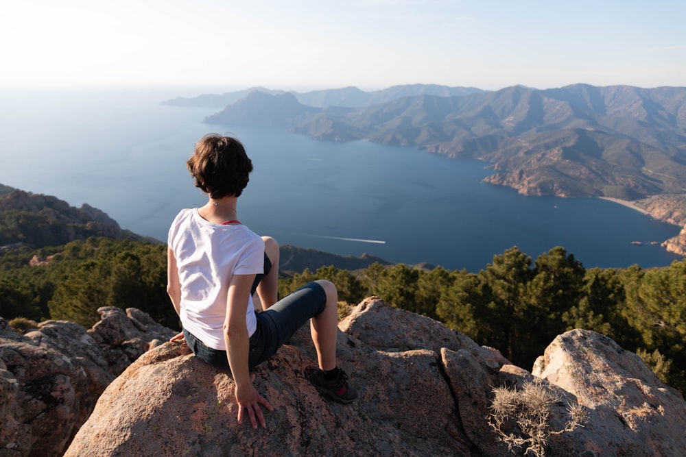 a person sitting on top of a large rock