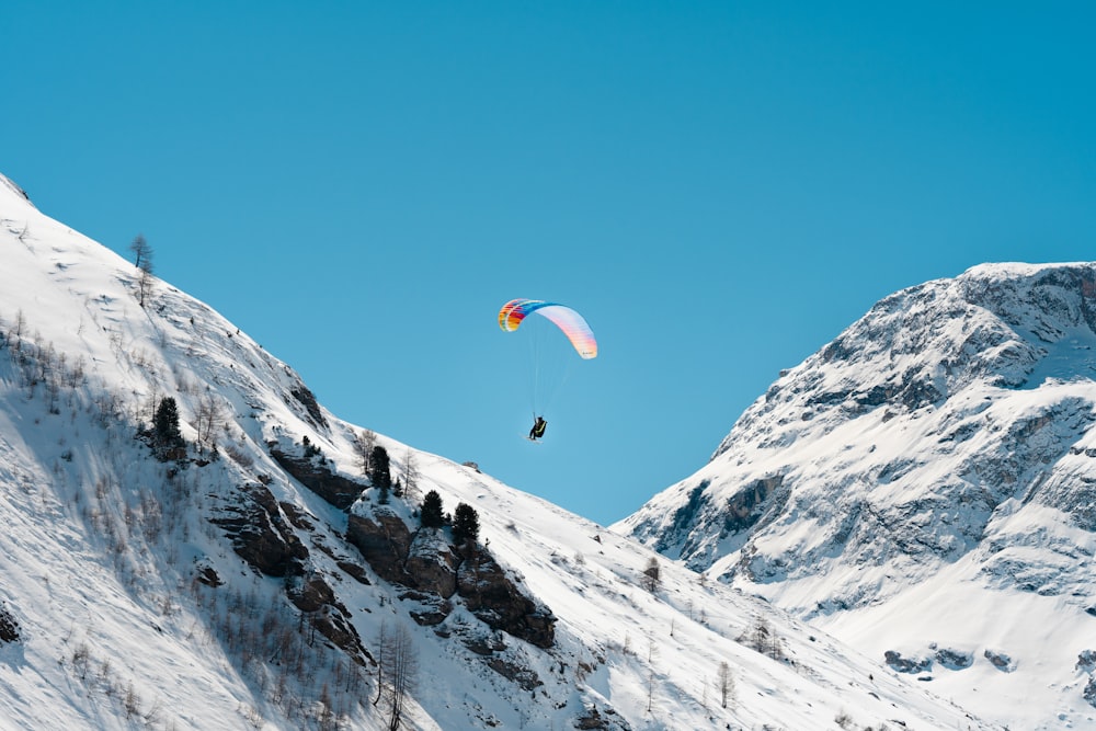 a paraglider is flying over a snowy mountain