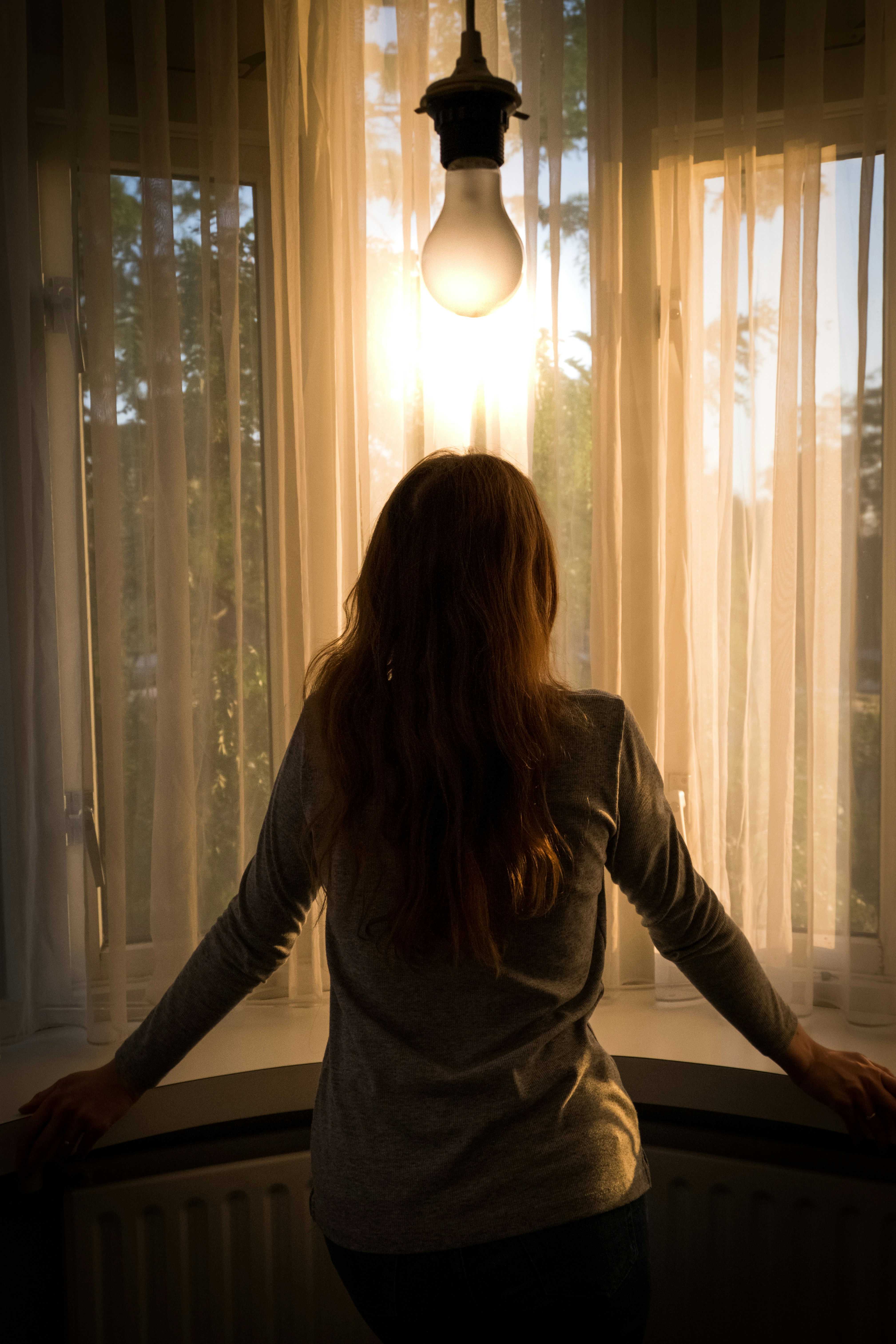 a woman standing in front of a window looking out