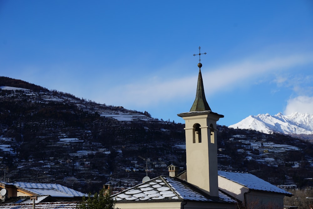 a church with a steeple and a snow covered mountain in the background