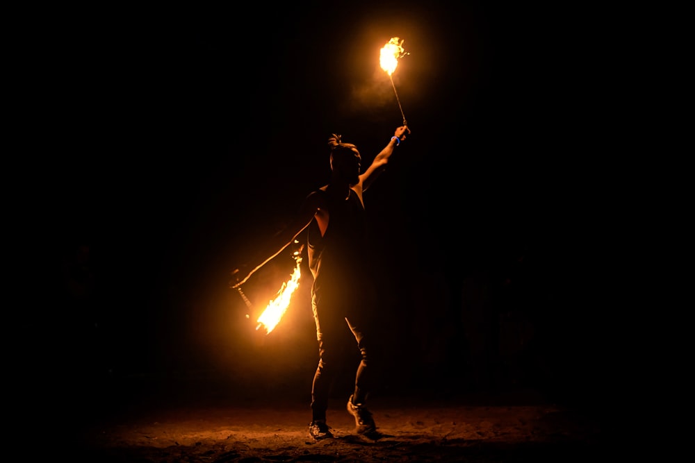 a person holding two torches in the dark