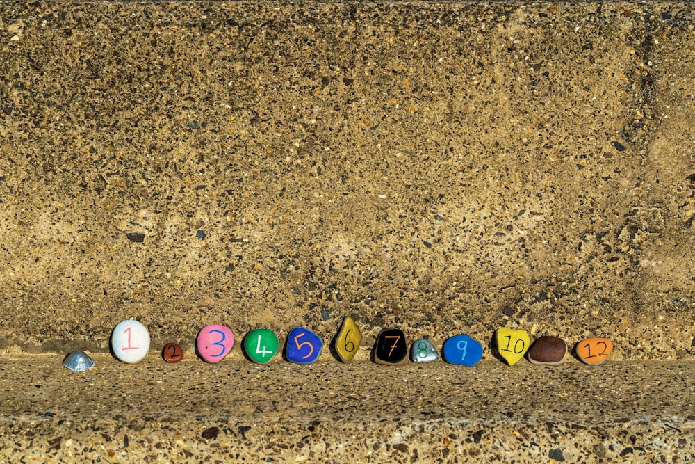 a row of colorful eggs sitting on top of a sandy ground