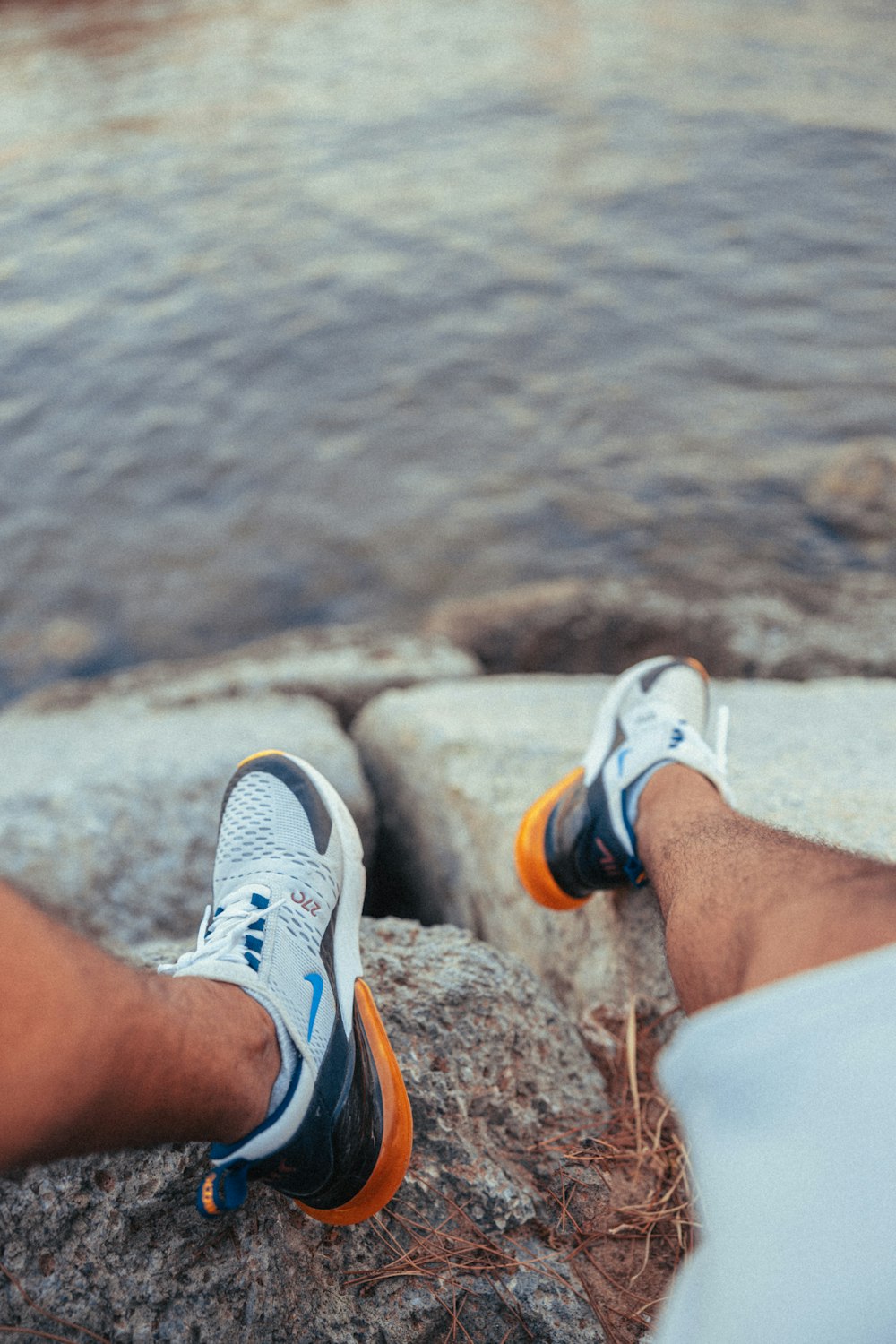 a person standing on a rock next to a body of water