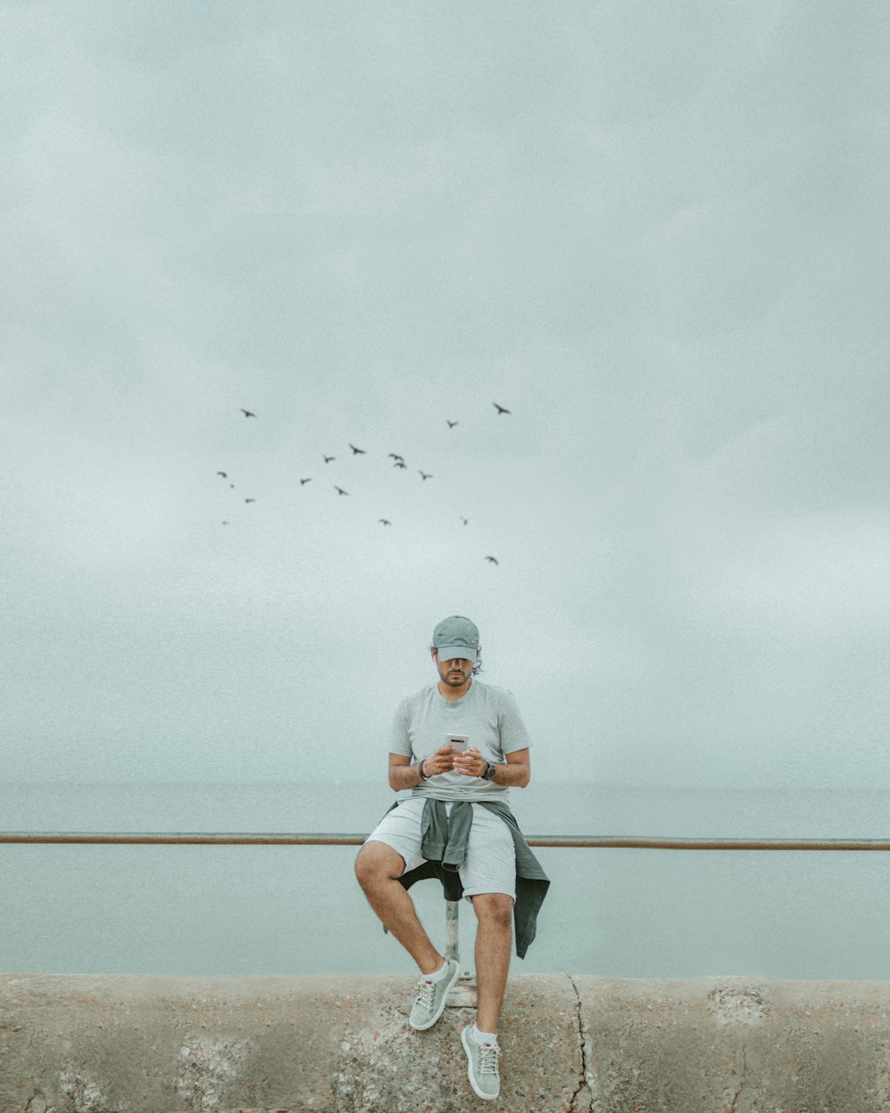 a man sitting on a wall looking at his cell phone