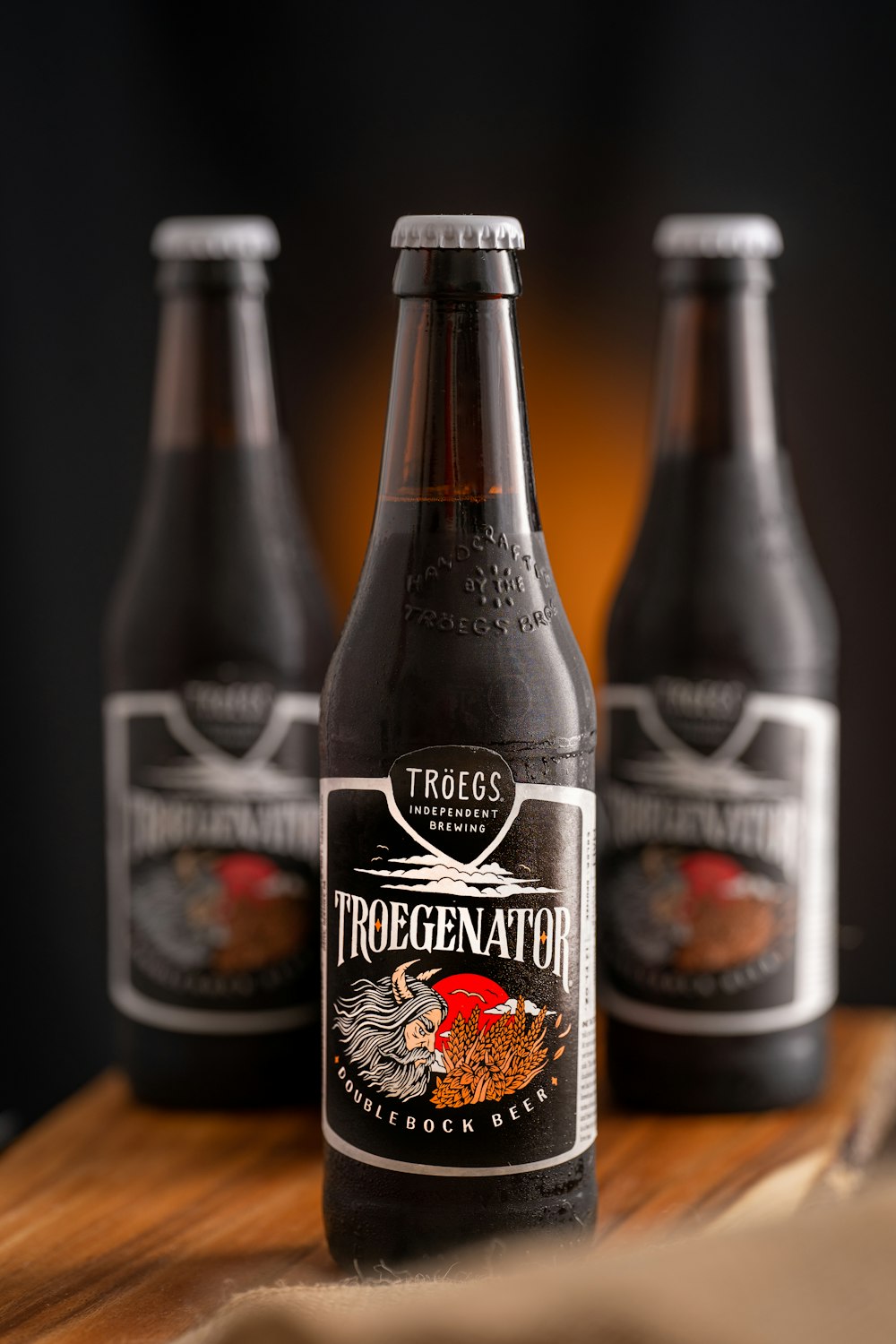 three bottles of beer sitting on top of a wooden table