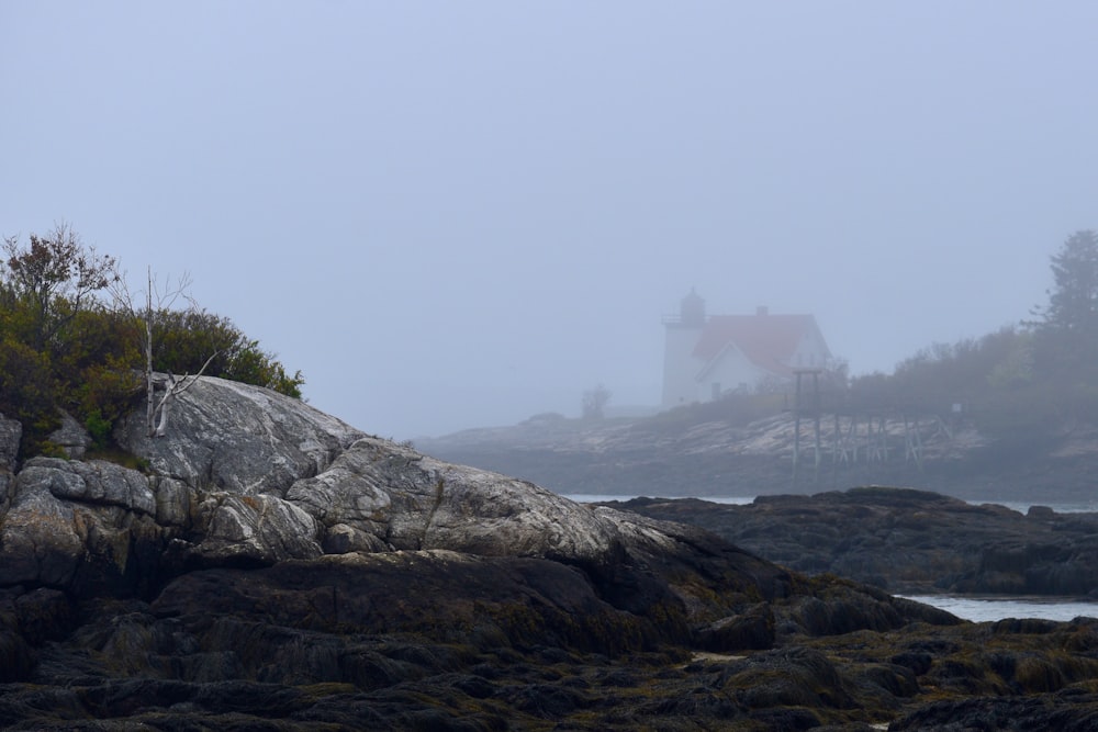 a lighthouse on a rocky shore in the fog