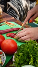 a person cutting up vegetables on a cutting board