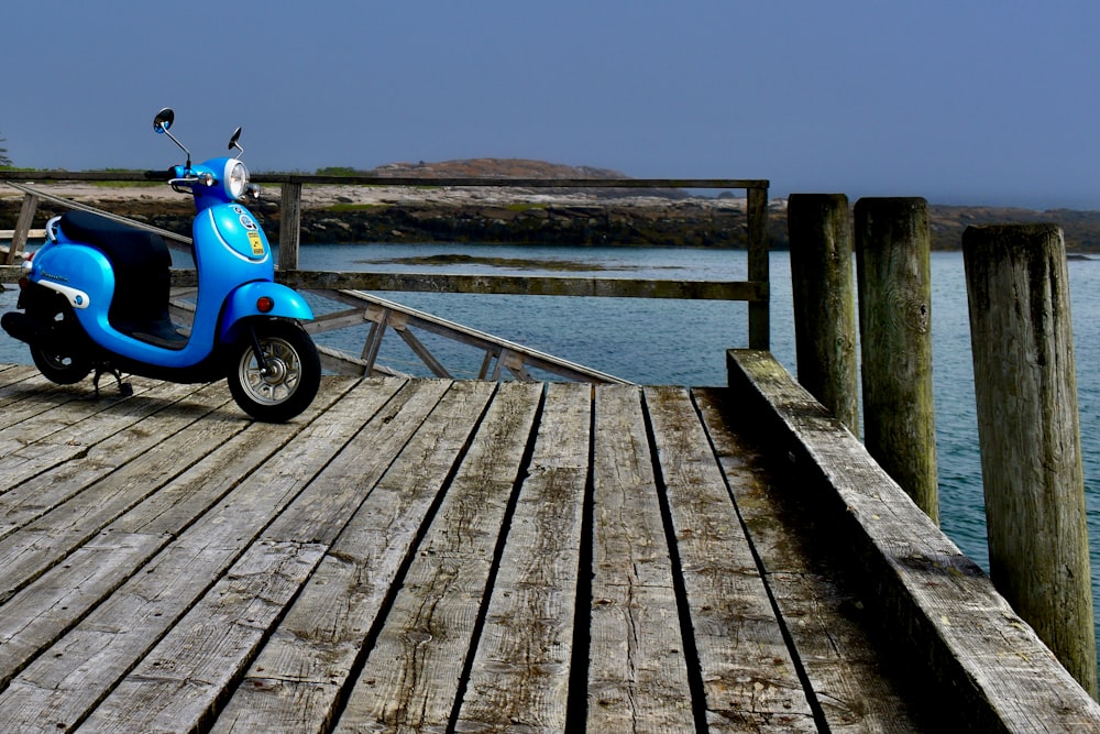 Un scooter azul estacionado en un muelle de madera