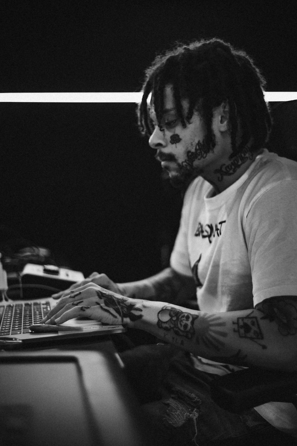 a man with dreadlocks sitting in front of a laptop