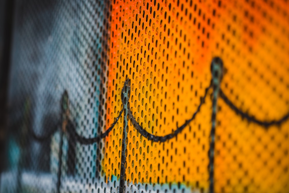 a close up of a fence with a yellow and orange background