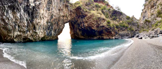a view of a beach with a rock arch in the water