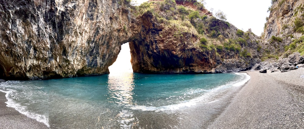 a view of a beach with a rock arch in the water