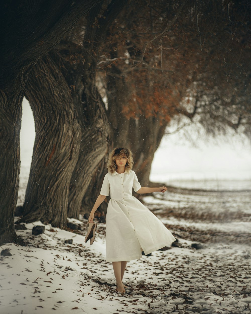 a woman in a white dress walking in the snow