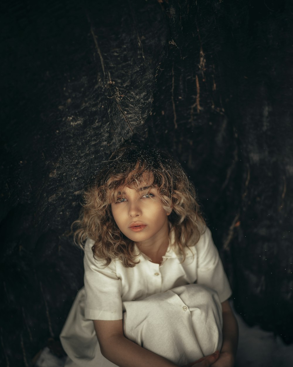 a young girl sitting in front of a black wall