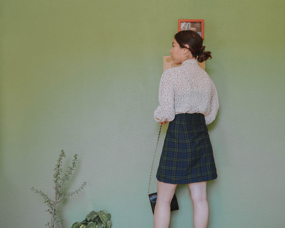 a woman standing against a wall with her hand on her hip