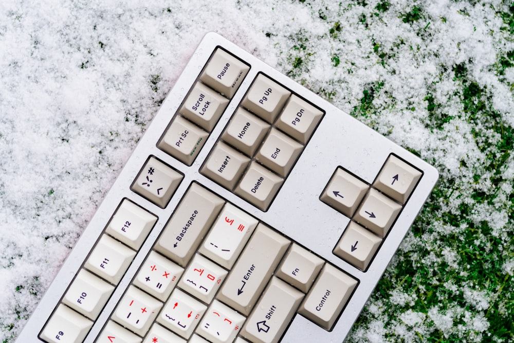 a computer keyboard sitting on top of snow covered ground