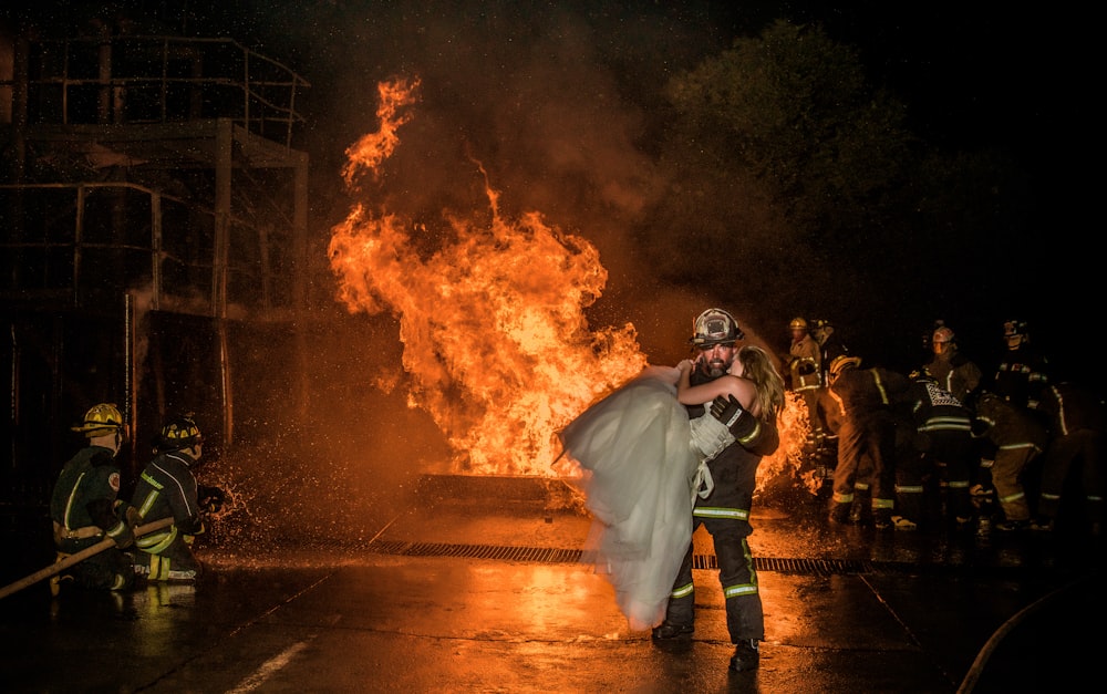 a bride and groom hug in front of a fire