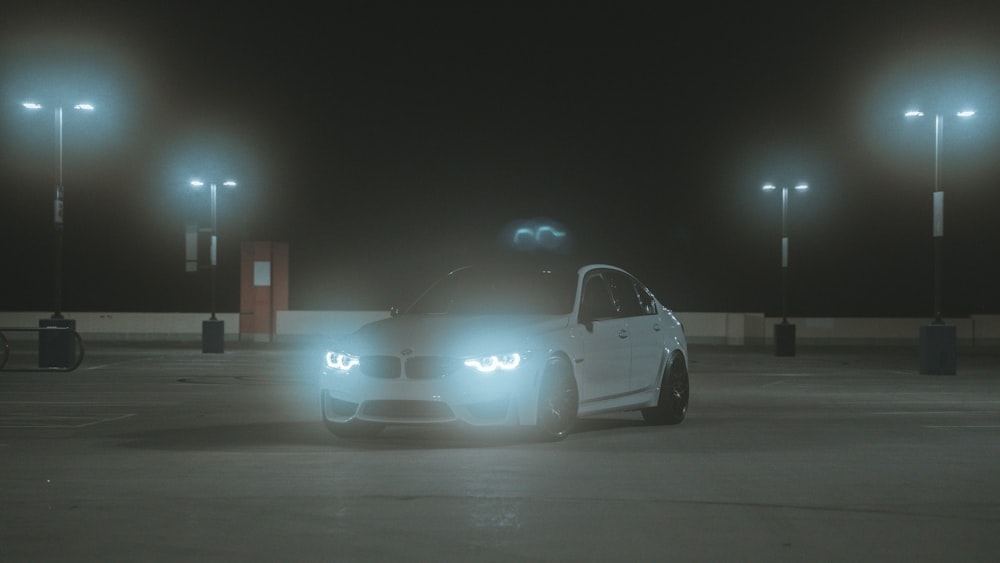 a white car parked in a parking lot at night