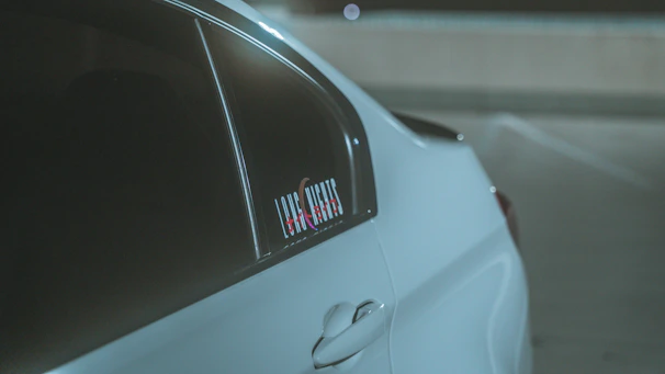 Factory decal applied perfectly on a white sports car door, highlighting its curves.