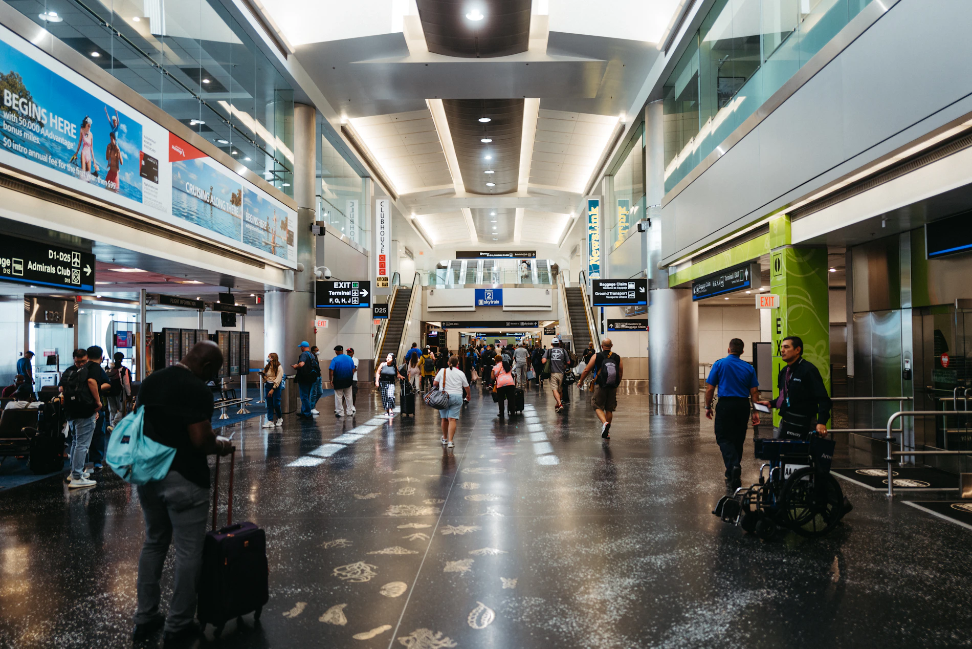 Travelers walking with luggage through a large airport terminal