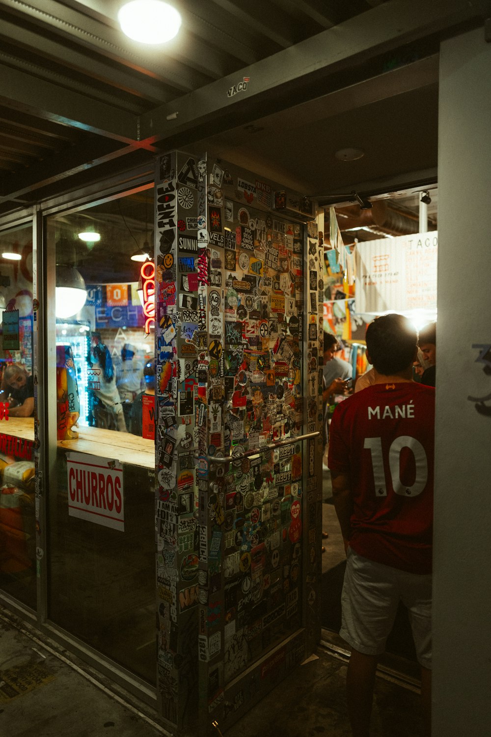um homem em pé na frente de uma loja com um monte de adesivos sobre ele