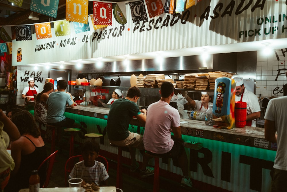 a group of people sitting at a counter in a restaurant