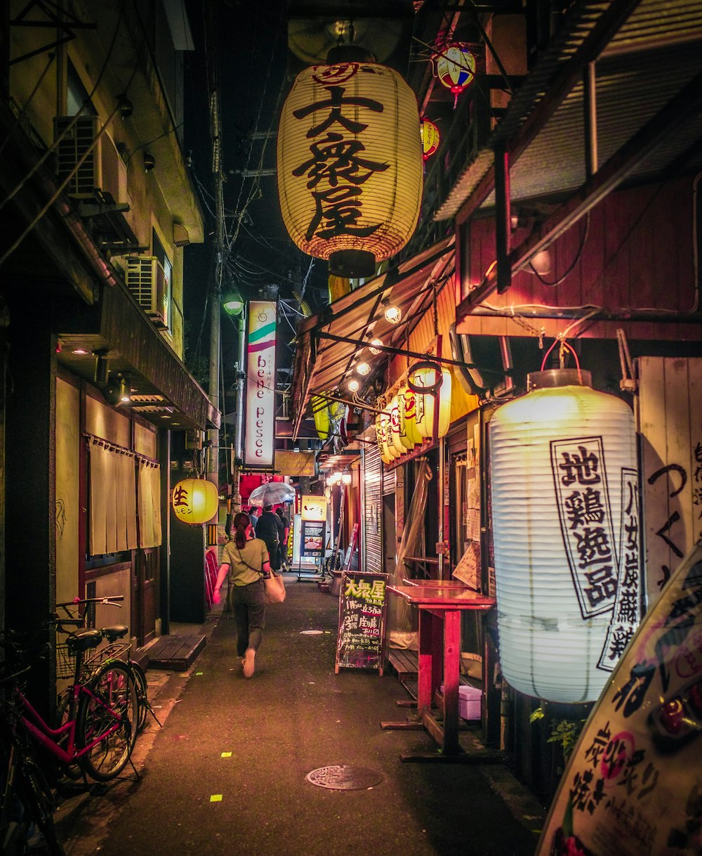 a narrow alley way with asian lanterns hanging from the ceiling