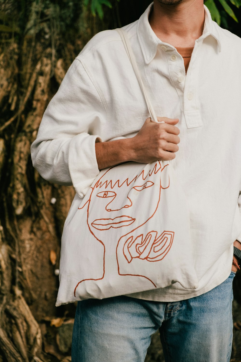 a man holding a bag with a drawing on it