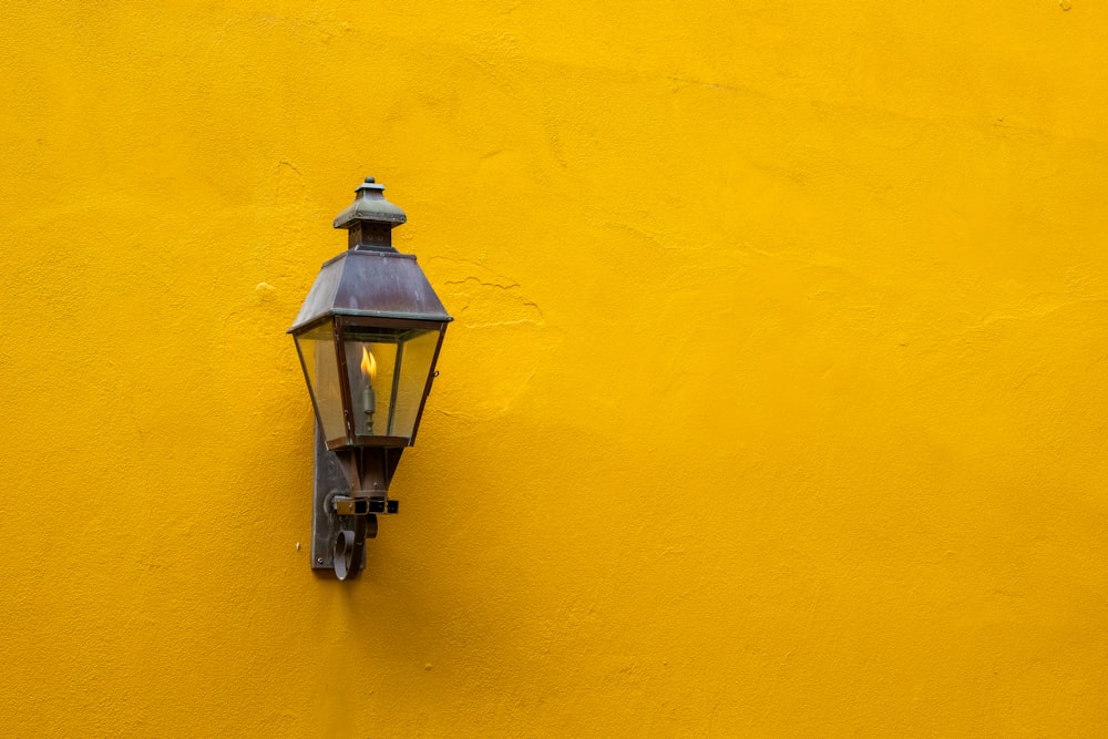 a lamp on the side of a yellow wall