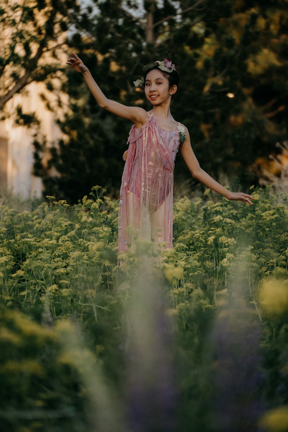 a young girl in a pink dress standing in a field of flowers