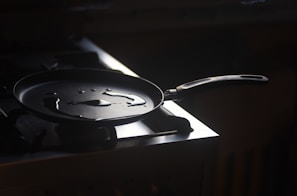 Close-up of a polished aluminum frying pan reflecting soft kitchen light