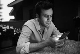 a man sitting at a table looking at a cell phone