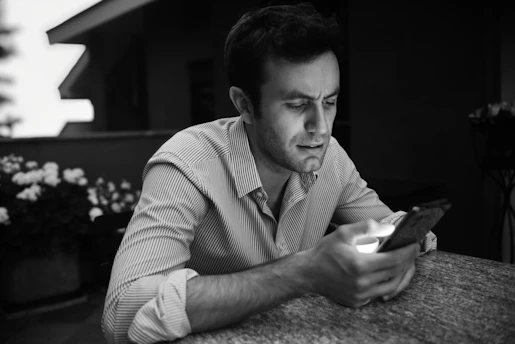 a man sitting at a table looking at a cell phone