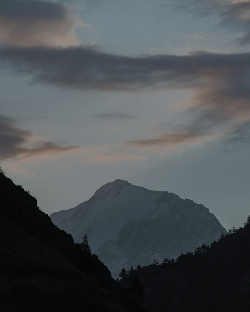 a view of a mountain at dusk with clouds in the sky