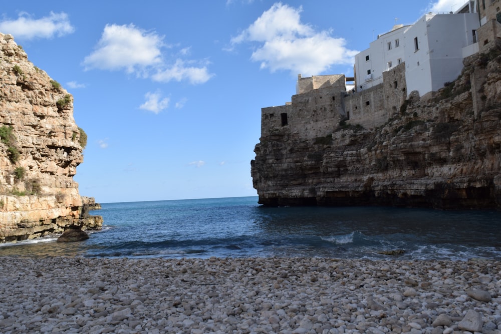 a rocky beach next to a cliff and a body of water