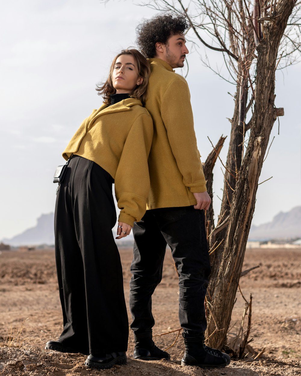 a man and a woman standing next to a tree