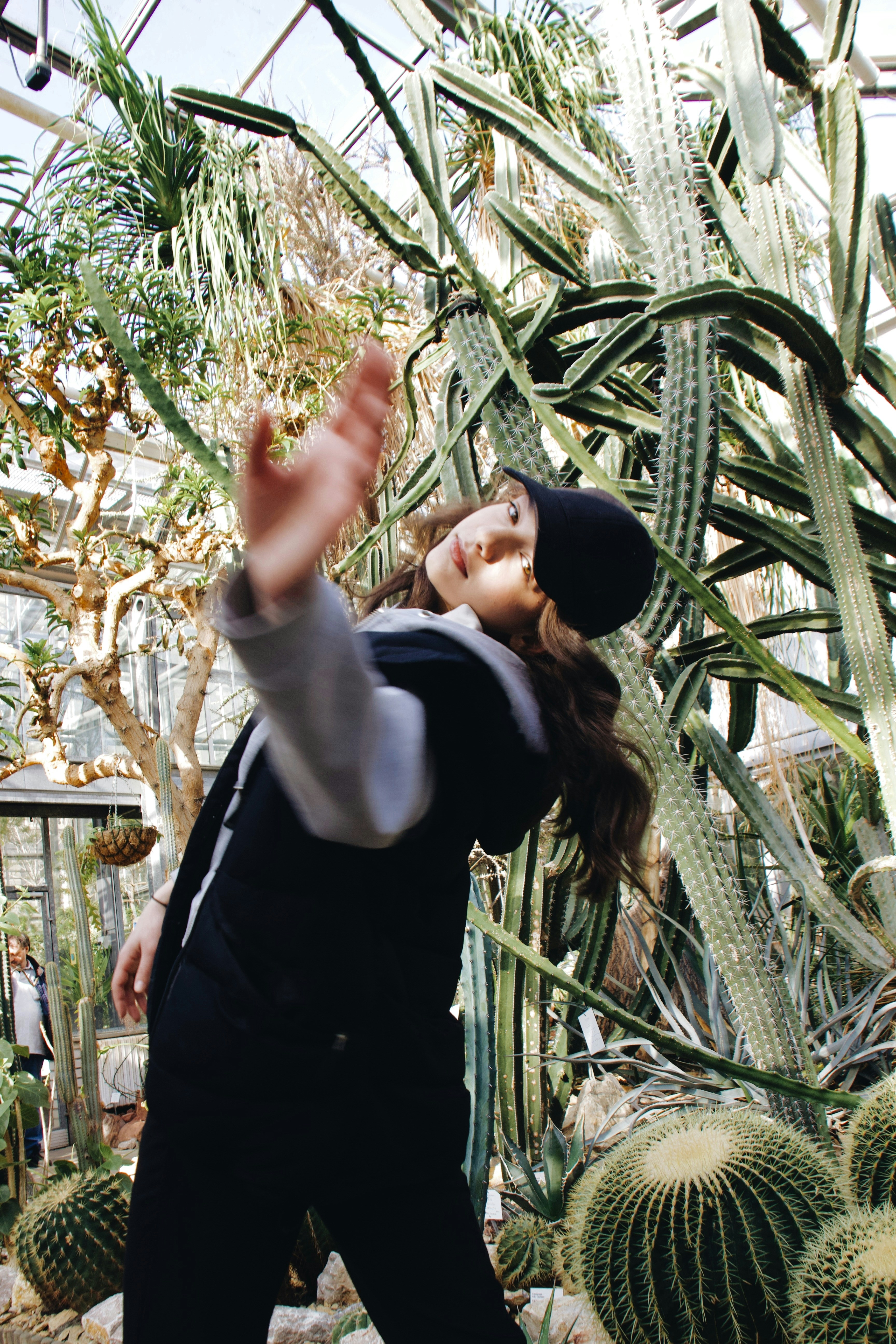 a woman standing in front of a cactus in a greenhouse
