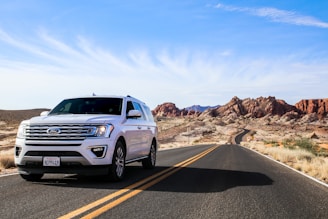 a white suv driving down a desert road
