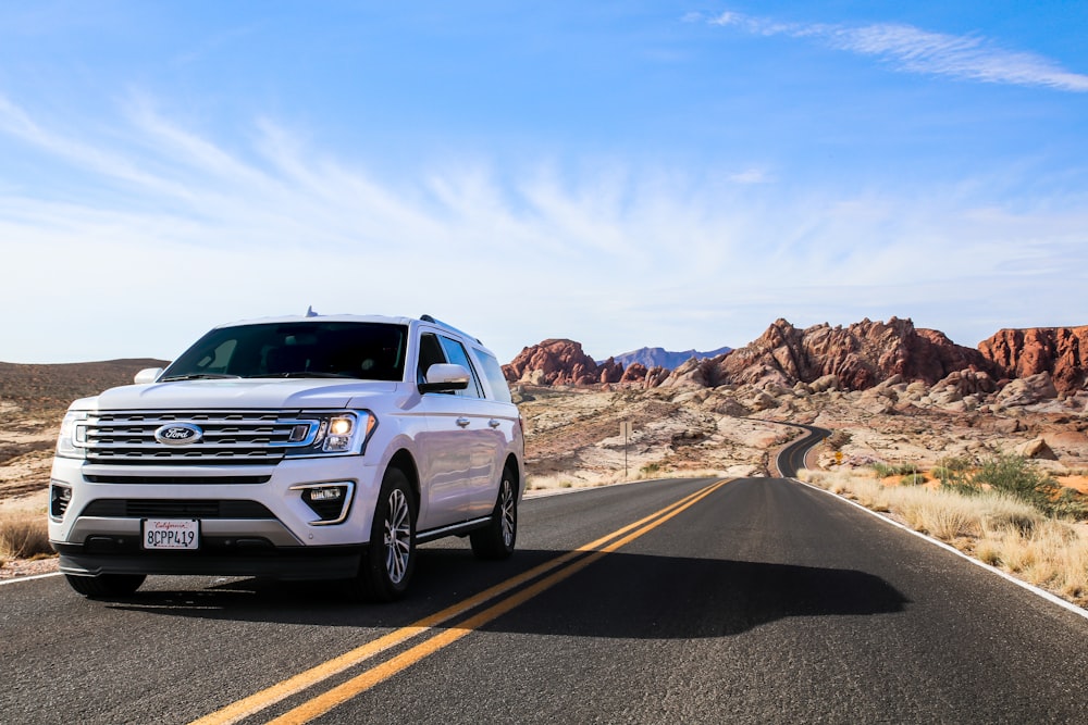 a white suv driving down a desert road