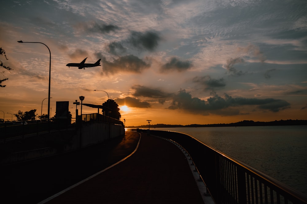 a plane flying over a body of water at sunset